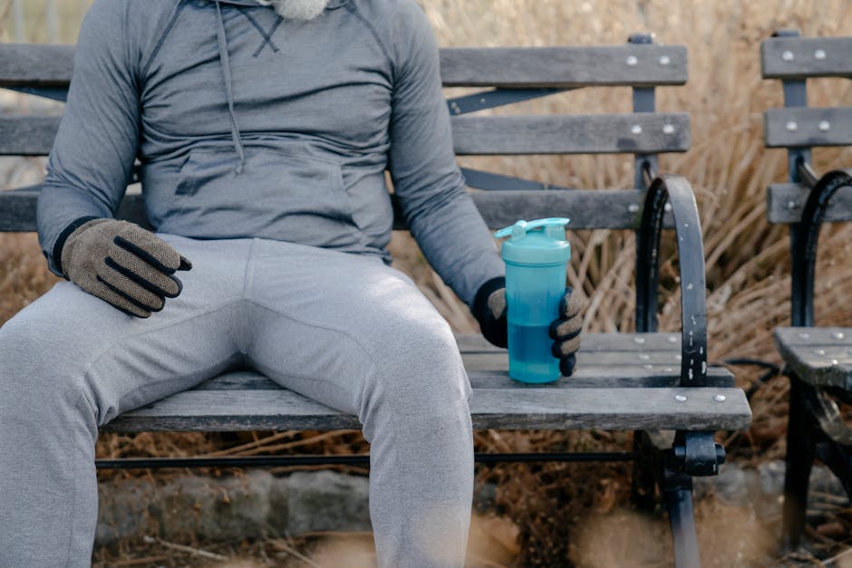 Man wearing headphones and casual sportswear is meditating while sitting on a city park bench